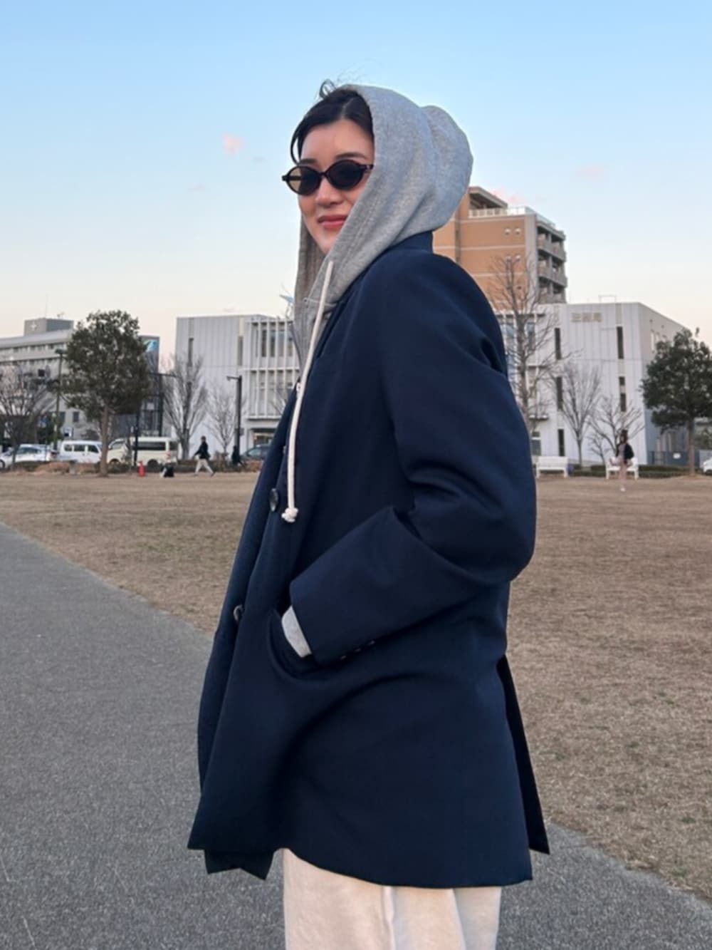 グレー系のパーカー、ブルー系のテーラードジャケット、ホワイト系のデニムパンツを着用したレディースの冬コーディネートの7枚目の写真