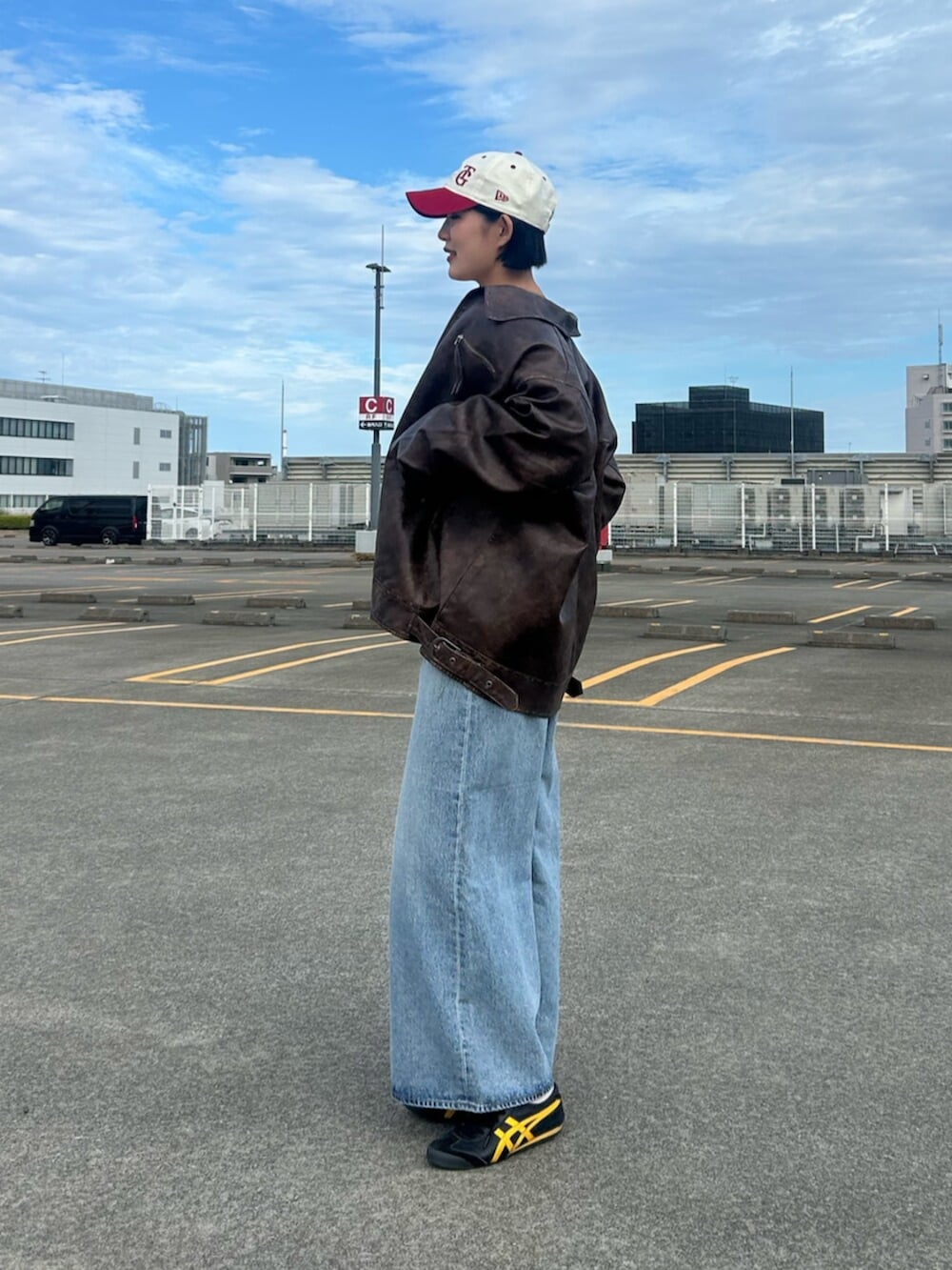 ブルー系のデニムパンツ、ブラウン系のブルゾン、ホワイト系のシャツ/ブラウスを着用したレディースの秋コーディネートの2枚目の写真