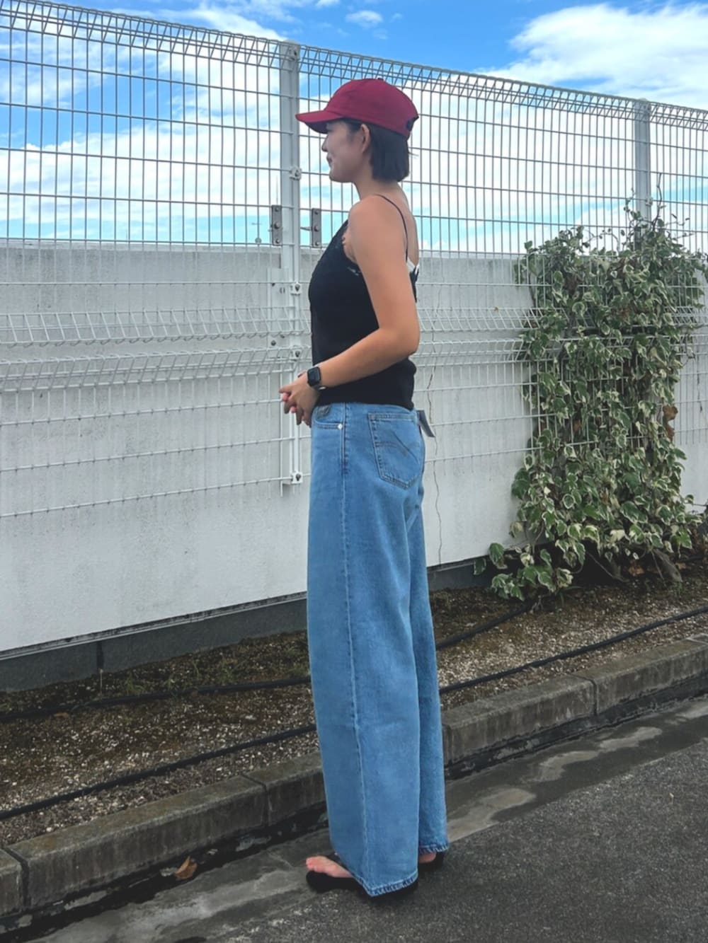 ブルー系のデニムパンツ、ブラック系のTシャツ/カットソー、レッド系のキャップを着用したレディースの夏コーディネートの2枚目の写真