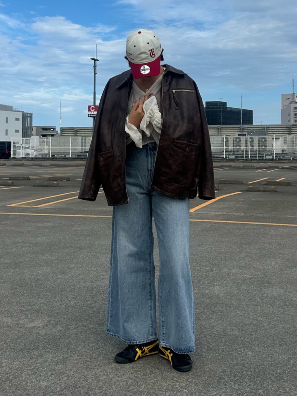 ブルー系のデニムパンツ、ブラウン系のブルゾン、ホワイト系のシャツ/ブラウスを着用したレディースの秋コーディネートの4枚目の写真