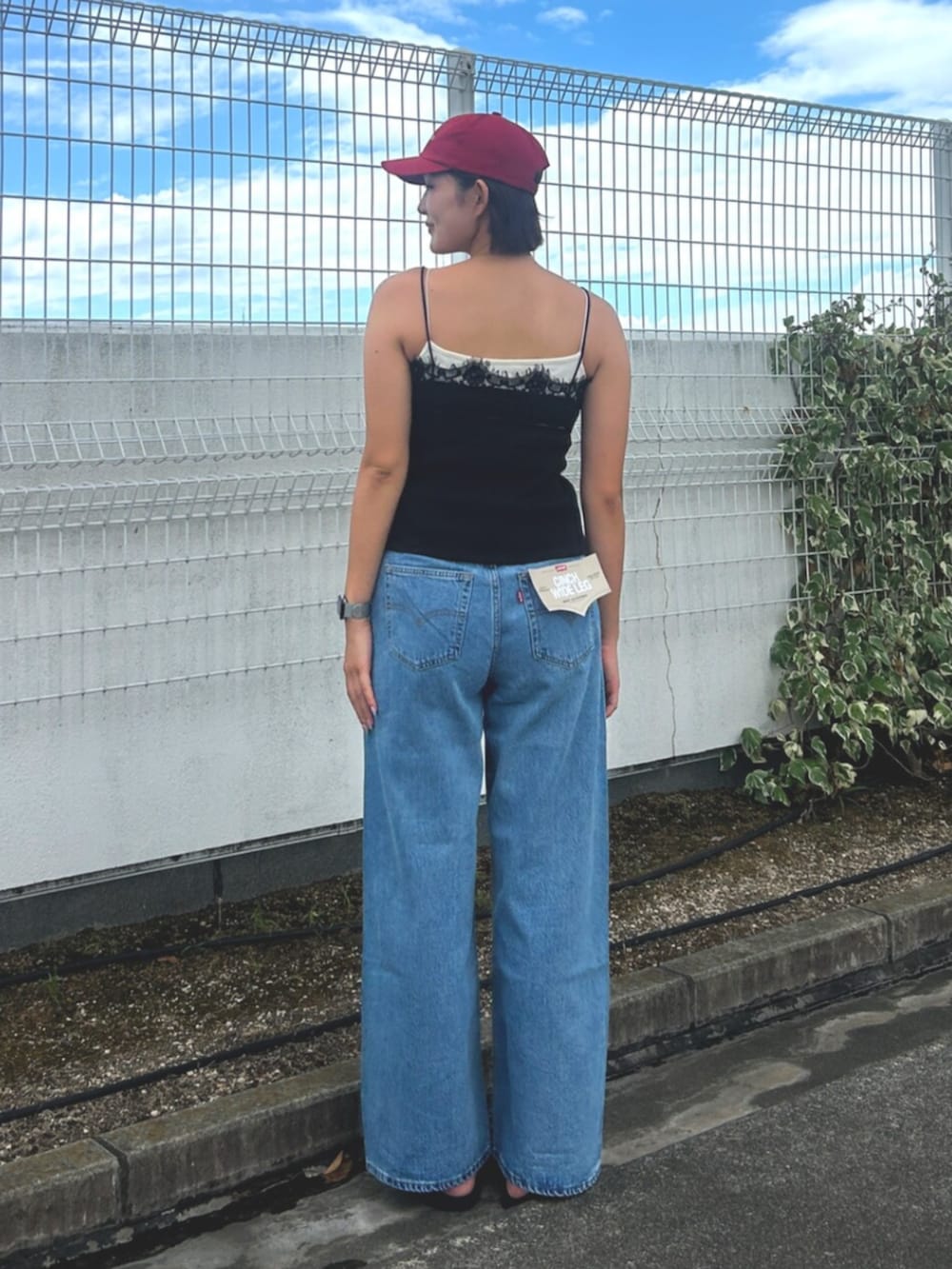 ブルー系のデニムパンツ、ブラック系のTシャツ/カットソー、レッド系のキャップを着用したレディースの夏コーディネートの3枚目の写真