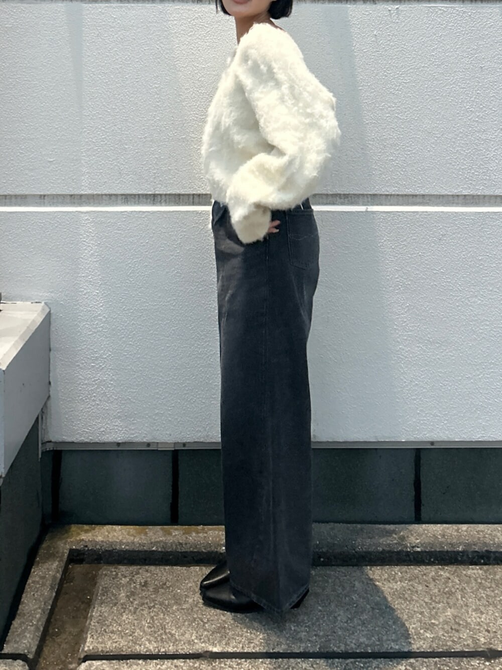 ホワイト系のニット/セーター、ブラック系のデニムパンツ、ブラック系のブーツを着用したレディースの秋コーディネートの2枚目の写真