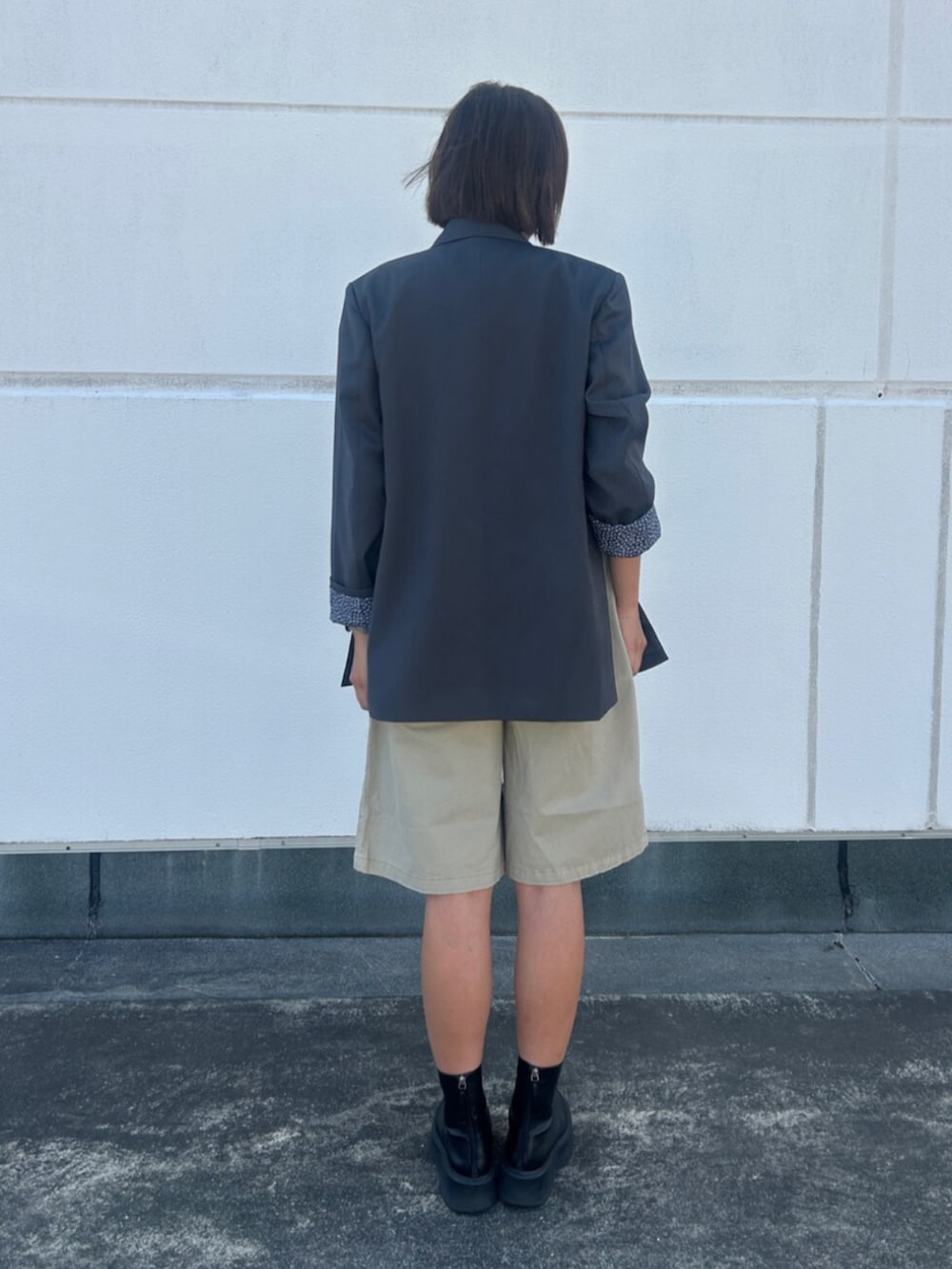 ベージュ系のデニムパンツ、グレー系のテーラードジャケット、レッド系のTシャツ/カットソーを着用したレディースの夏コーディネートの3枚目の写真