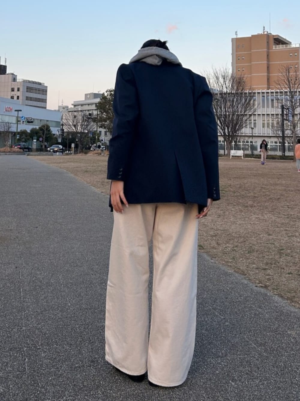 グレー系のパーカー、ブルー系のテーラードジャケット、ホワイト系のデニムパンツを着用したレディースの冬コーディネートの3枚目の写真