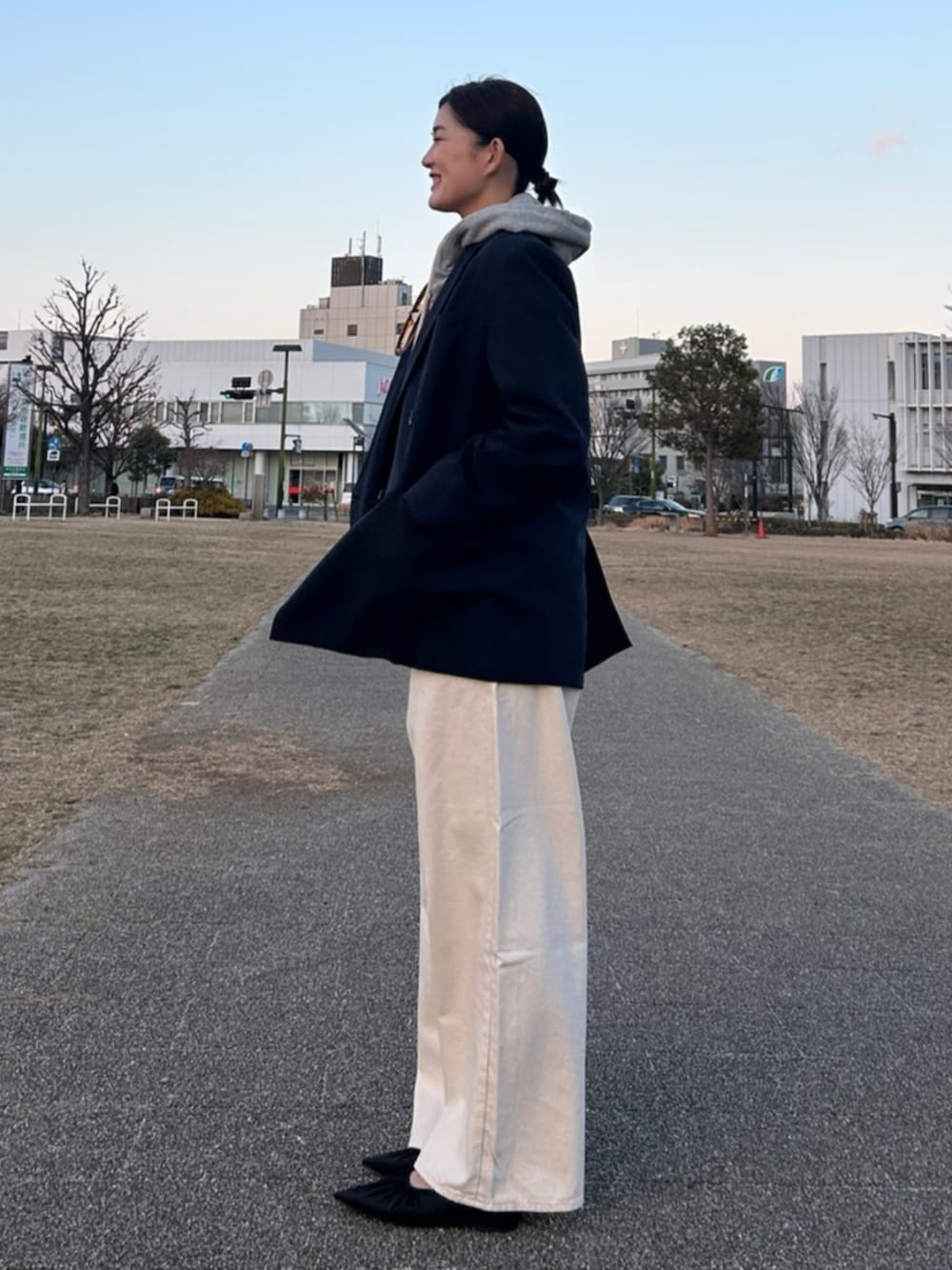 グレー系のパーカー、ブルー系のテーラードジャケット、ホワイト系のデニムパンツを着用したレディースの冬コーディネートの2枚目の写真