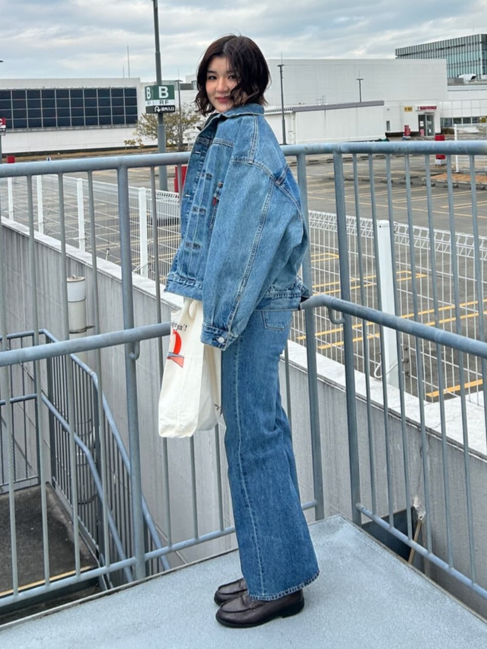 ブルー系のデニムパンツ、ブルー系のデニムジャケット、レッド系のTシャツ/カットソーを着用したレディースの冬コーディネートの2枚目の写真