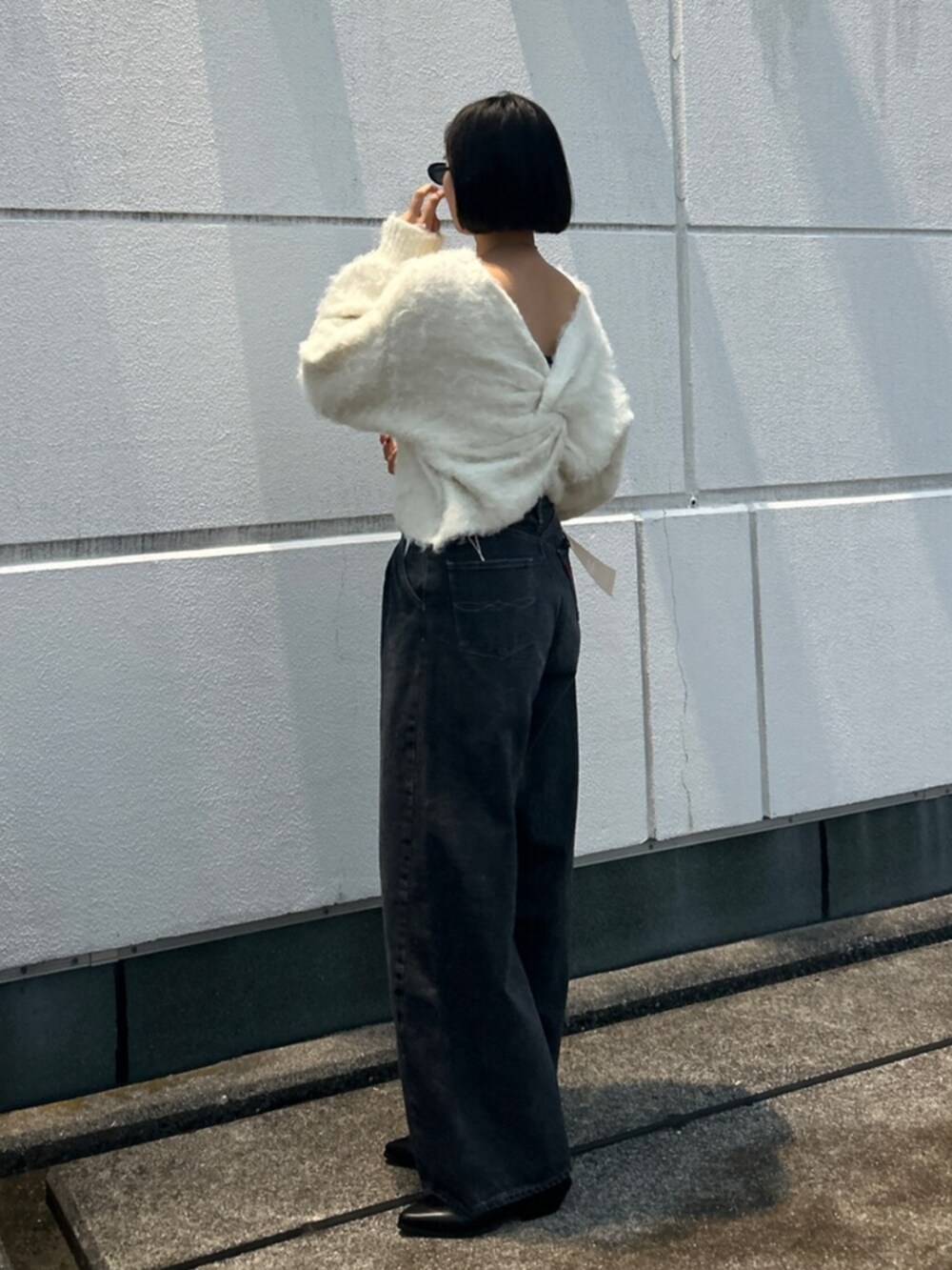 ホワイト系のニット/セーター、ブラック系のデニムパンツ、ブラック系のブーツを着用したレディースの秋コーディネートの4枚目の写真