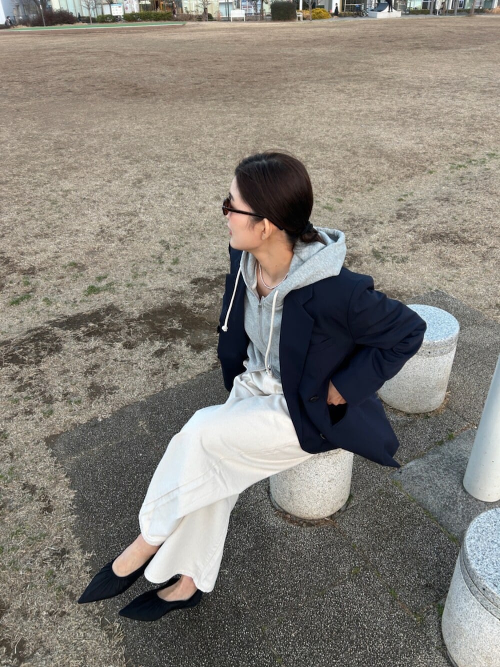 グレー系のパーカー、ブルー系のテーラードジャケット、ホワイト系のデニムパンツを着用したレディースの冬コーディネートの4枚目の写真