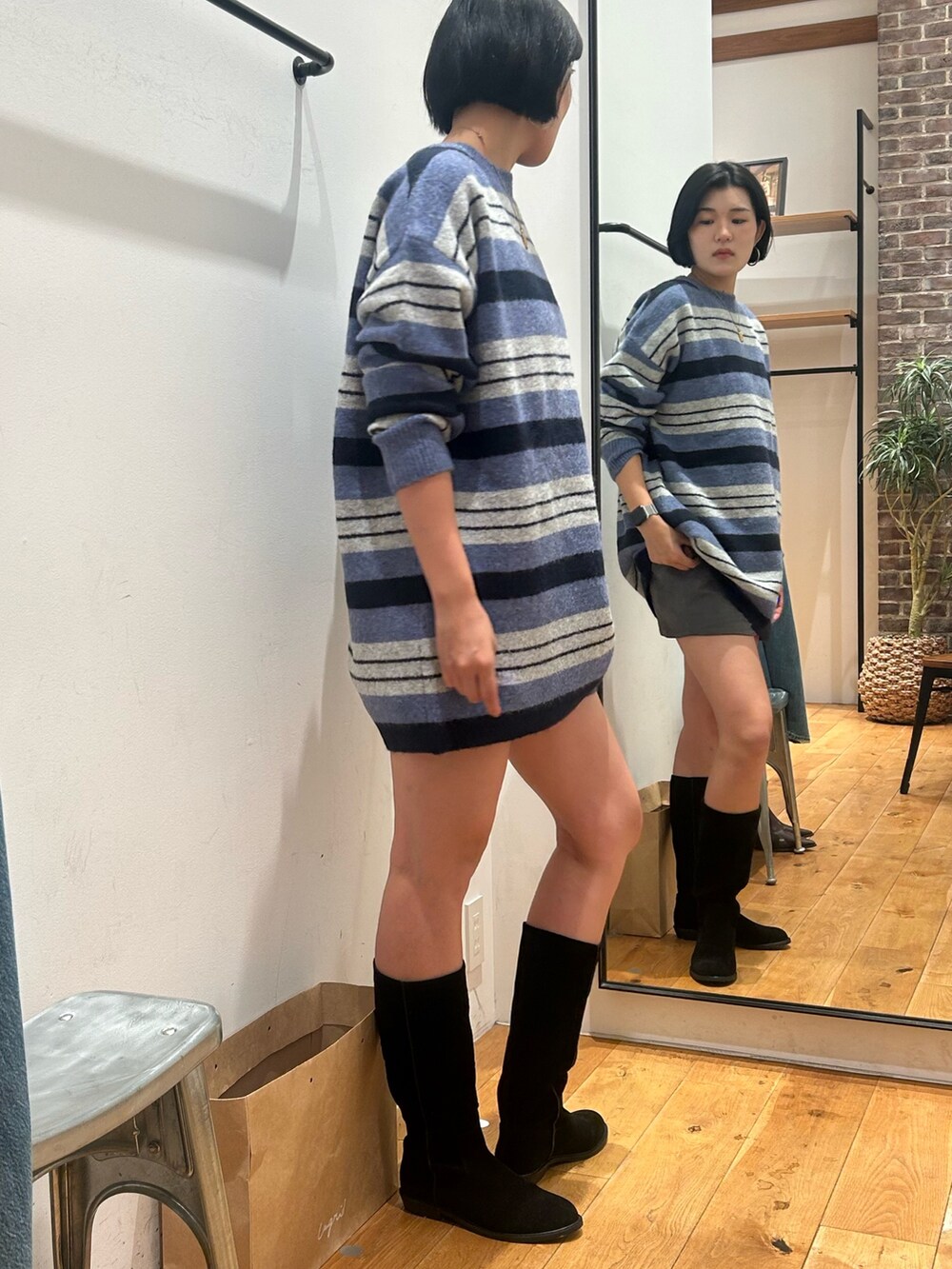 ブルー系のニット/セーター、ブラック系のブーツ、ブルー系のマフラーを着用したレディースの秋コーディネートの2枚目の写真