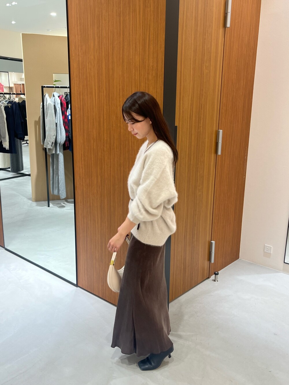 ホワイト系のニット/セーター、ホワイト系のハンドバッグ、ブラウン系のスカートを着用したレディースの冬コーディネートの4枚目の写真