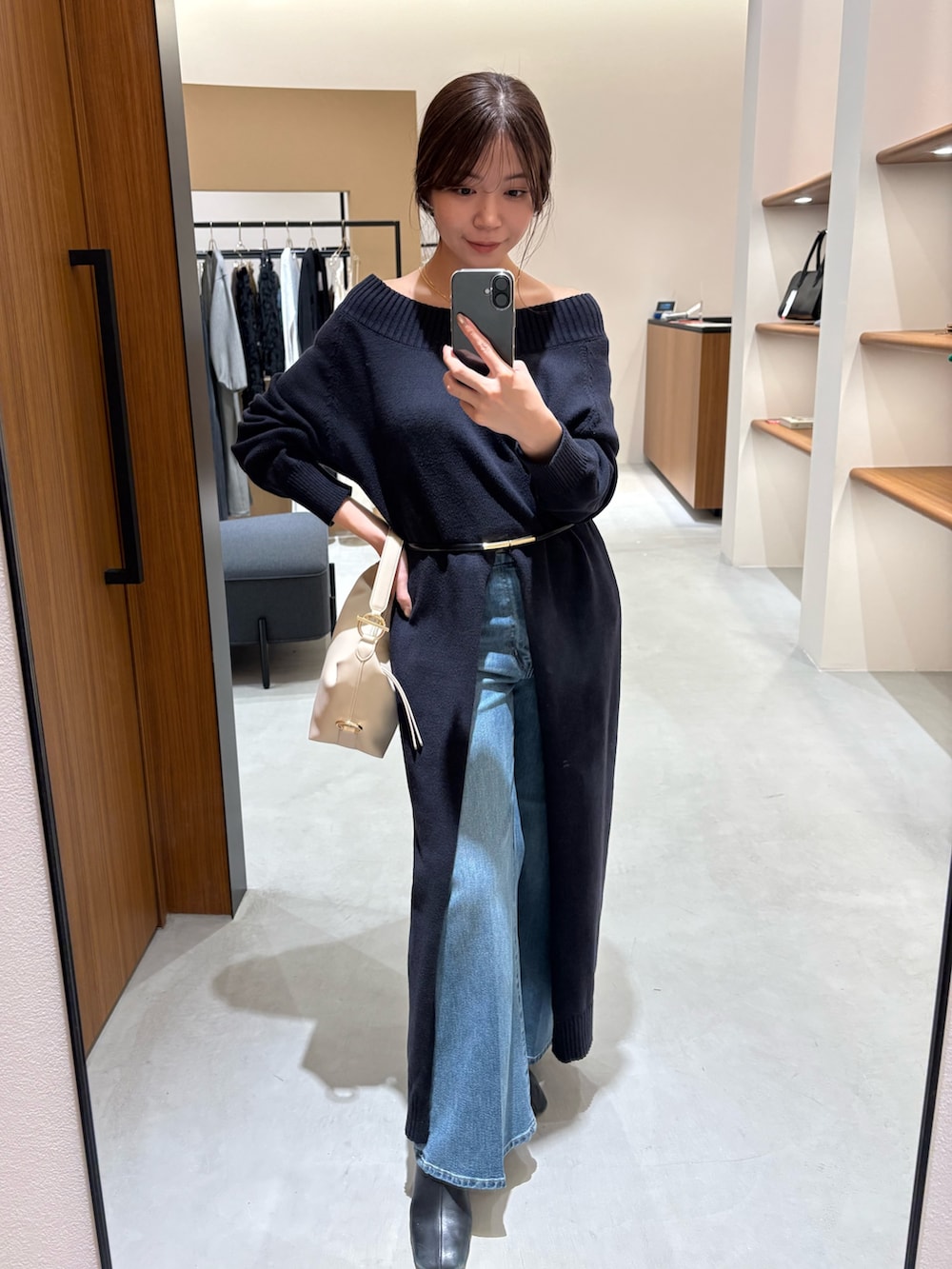 ブルー系のワンピース、ベージュ系のハンドバッグ、ブルー系のデニムパンツを着用したレディースの冬コーディネートの2枚目の写真