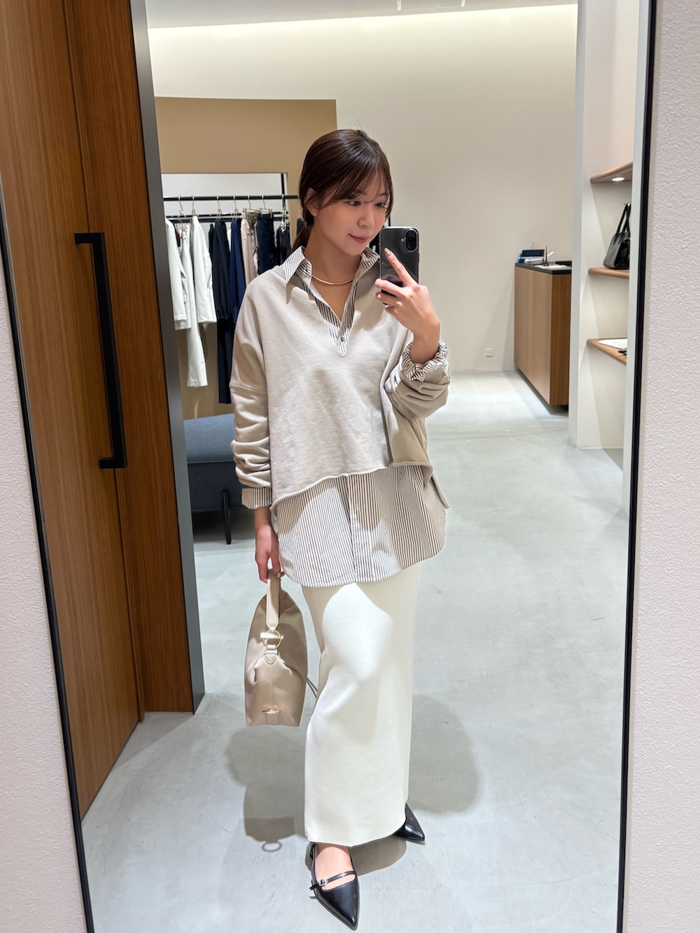 ホワイト系のスカート、ブラック系のパンプス、ベージュ系のハンドバッグを着用したレディースの春コーディネートの3枚目の写真
