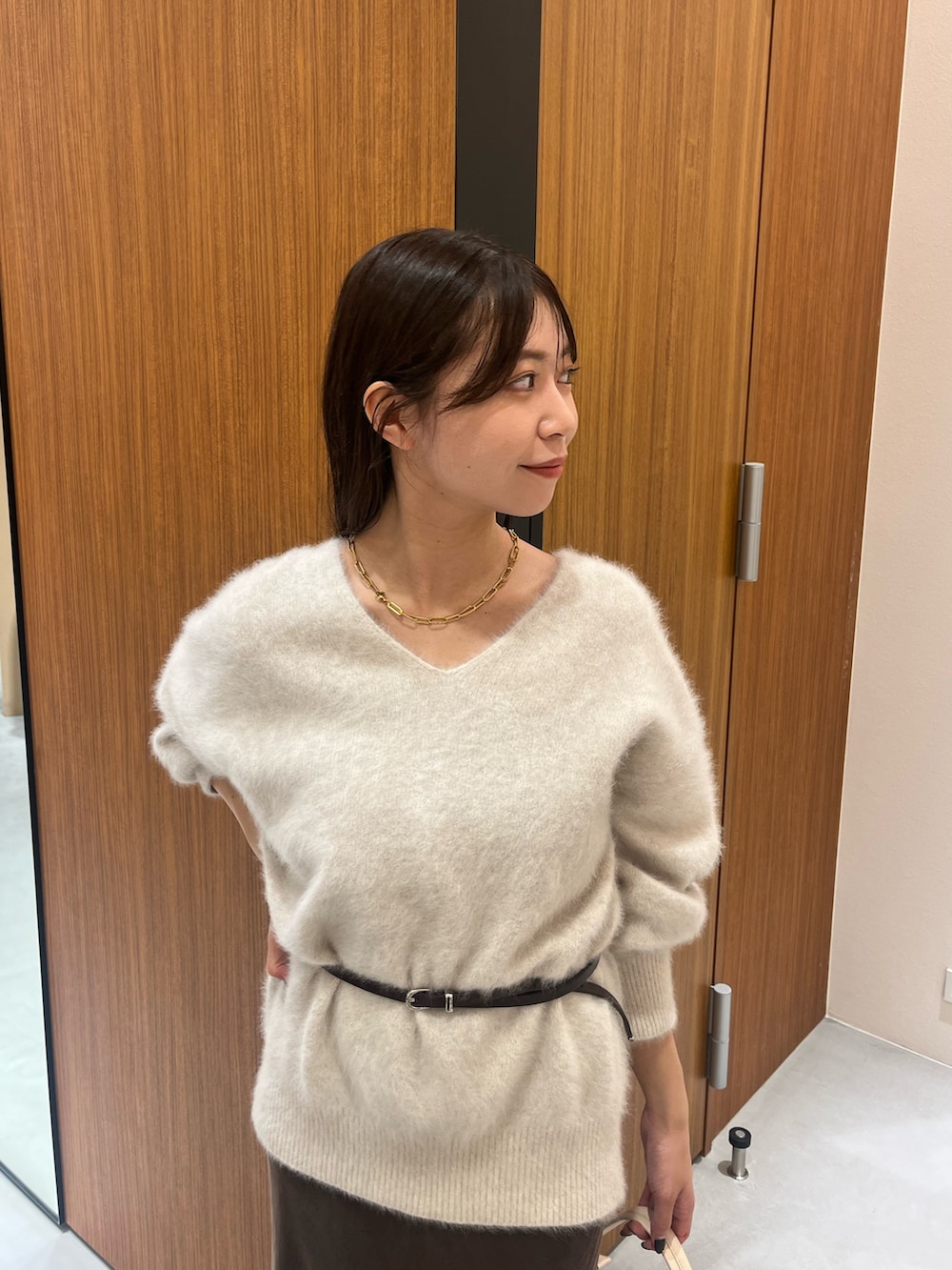 ホワイト系のニット/セーター、ホワイト系のハンドバッグ、ブラウン系のスカートを着用したレディースの冬コーディネートの2枚目の写真