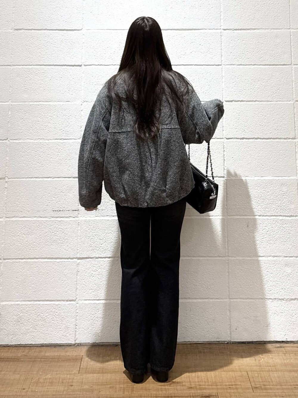 グレー系のブルゾン、ブラック系のデニムパンツ、ホワイト系のニット/セーターを着用したレディースの秋コーディネートの3枚目の写真