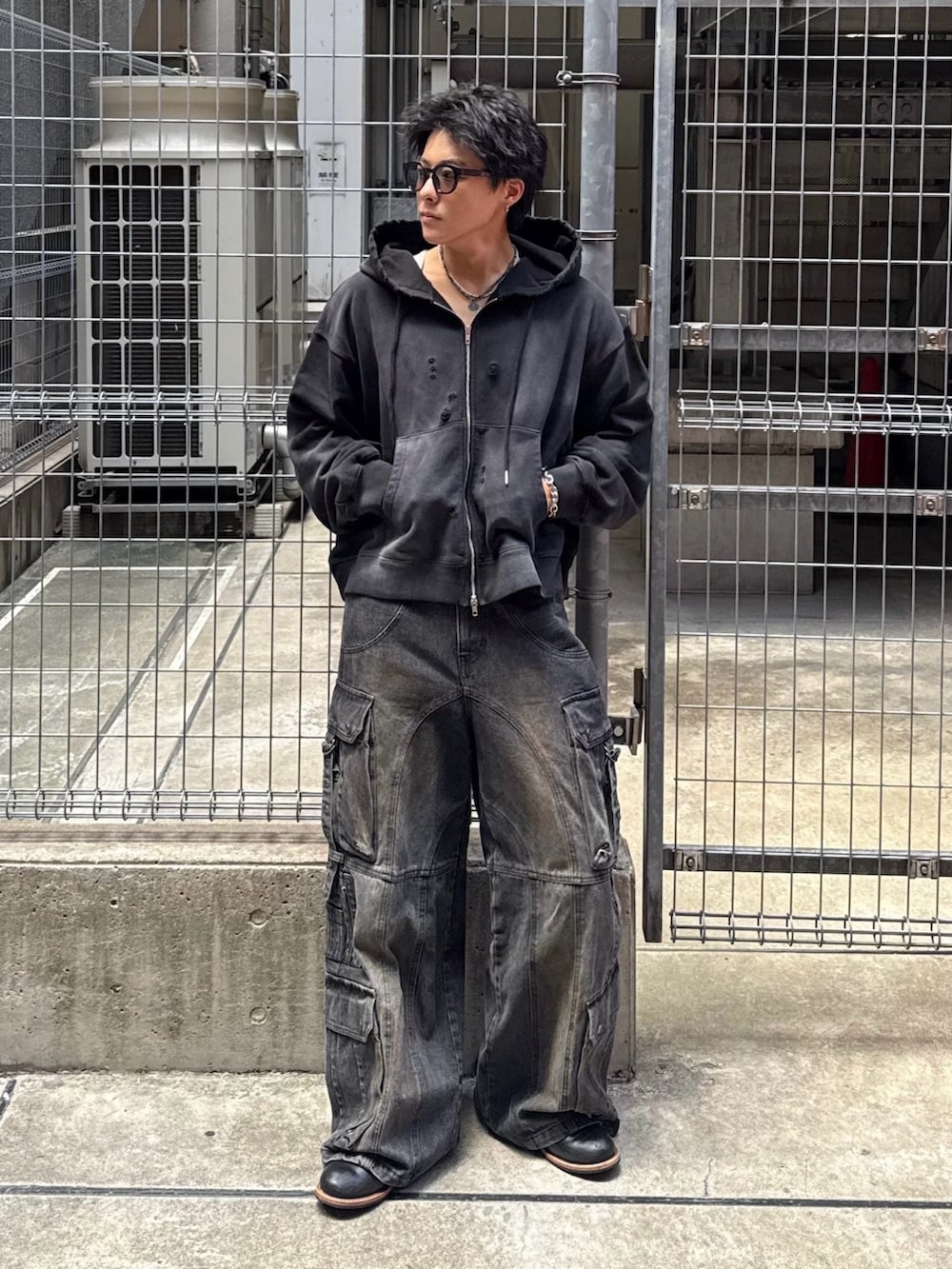 ブラック系のパーカー、ブラック系のデニムパンツ、ブラック系のブーツを着用したメンズの秋コーディネートの2枚目の写真