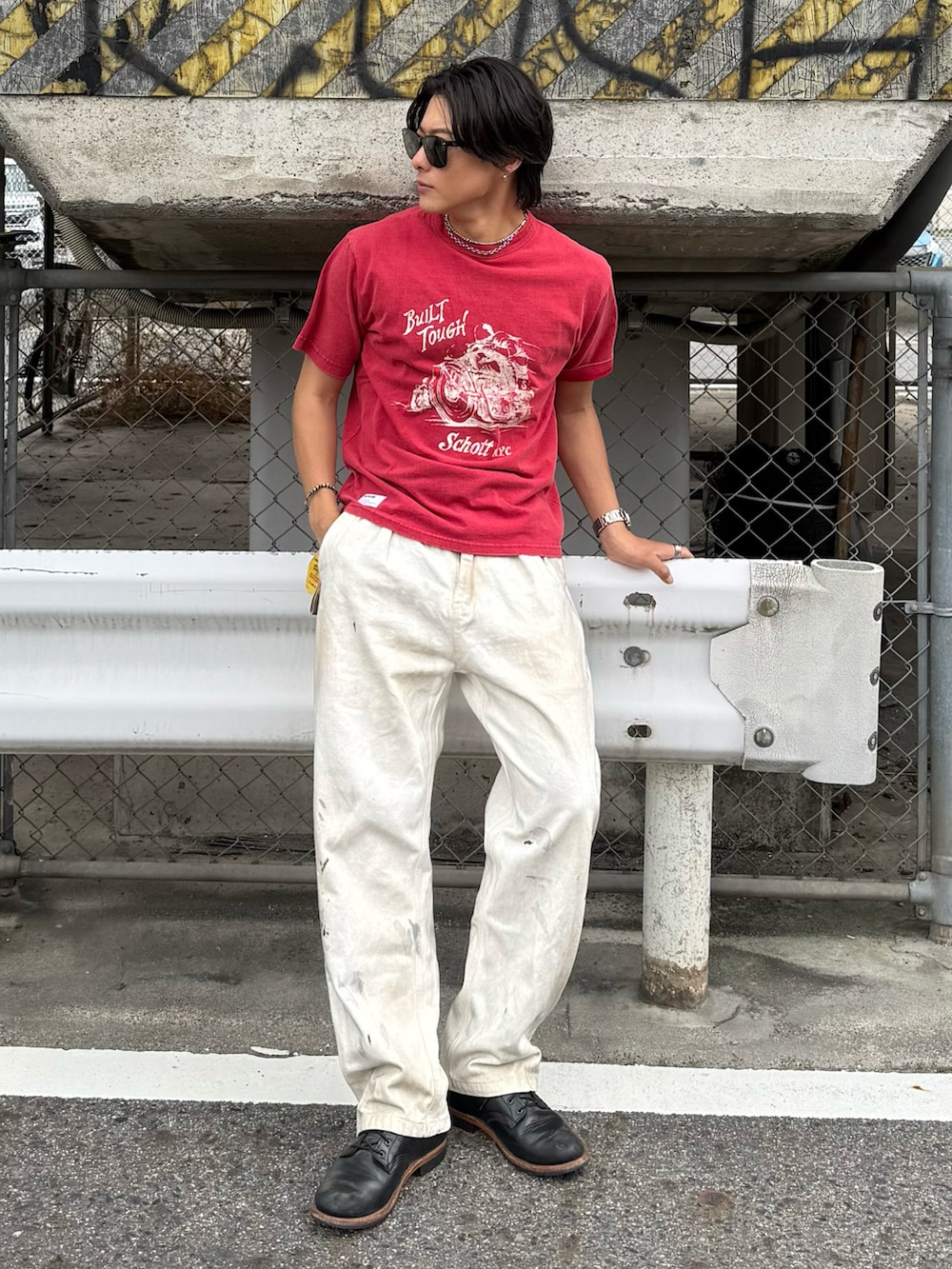 レッド系のTシャツ/カットソー、ブラック系のブーツ、ホワイト系のパンツを着用したメンズの春コーディネートの2枚目の写真