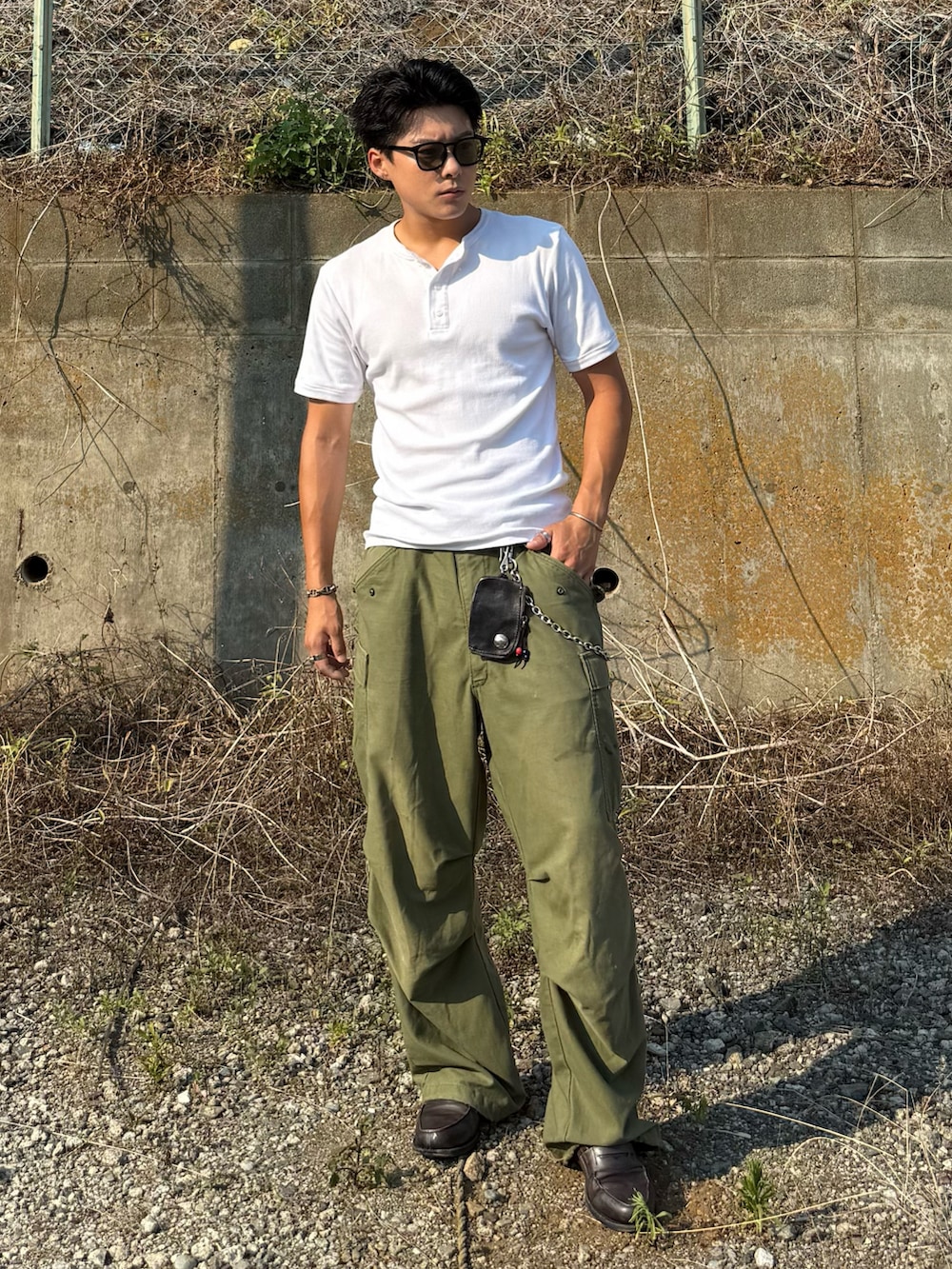 ホワイト系のTシャツ/カットソー、グレー系のローファー、グリーン系のパンツを着用したメンズの夏コーディネートの2枚目の写真