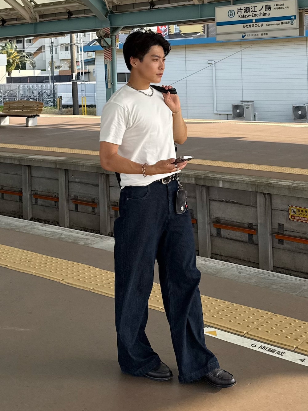 ブラック系のショルダーバッグ、ホワイト系のTシャツ/カットソー、ブルー系のデニムパンツを着用したメンズの春コーディネートの2枚目の写真
