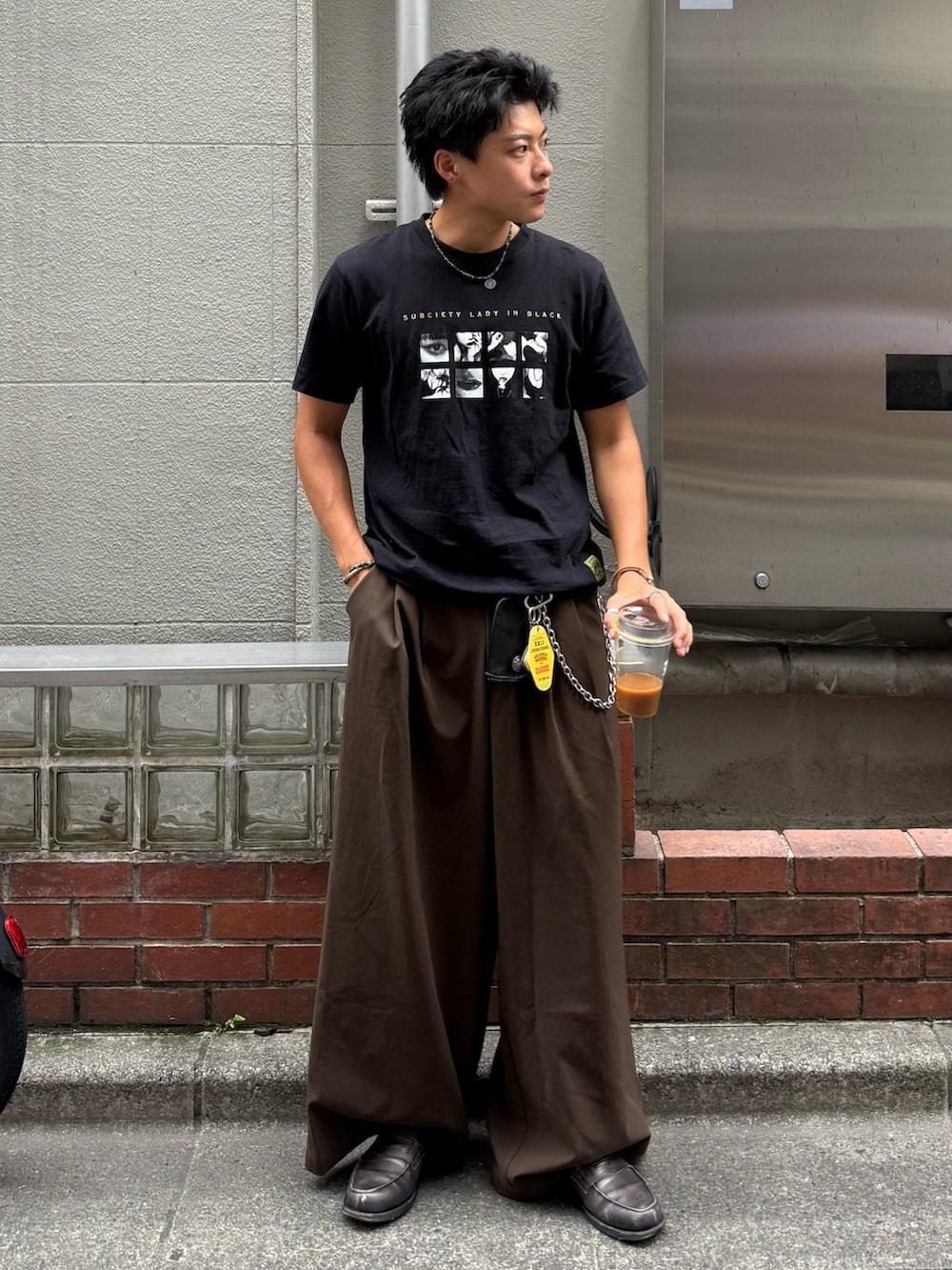 ブラック系のTシャツ/カットソー、ブラウン系のスラックス、グレー系のローファーを着用したメンズの夏コーディネートの2枚目の写真