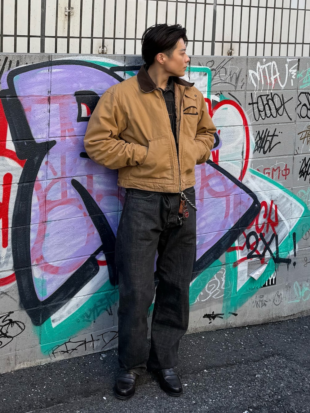 ブラウン系のブルゾン、ブラック系のデニムジャケット、ブラック系のデニムパンツを着用したメンズの春コーディネートの3枚目の写真