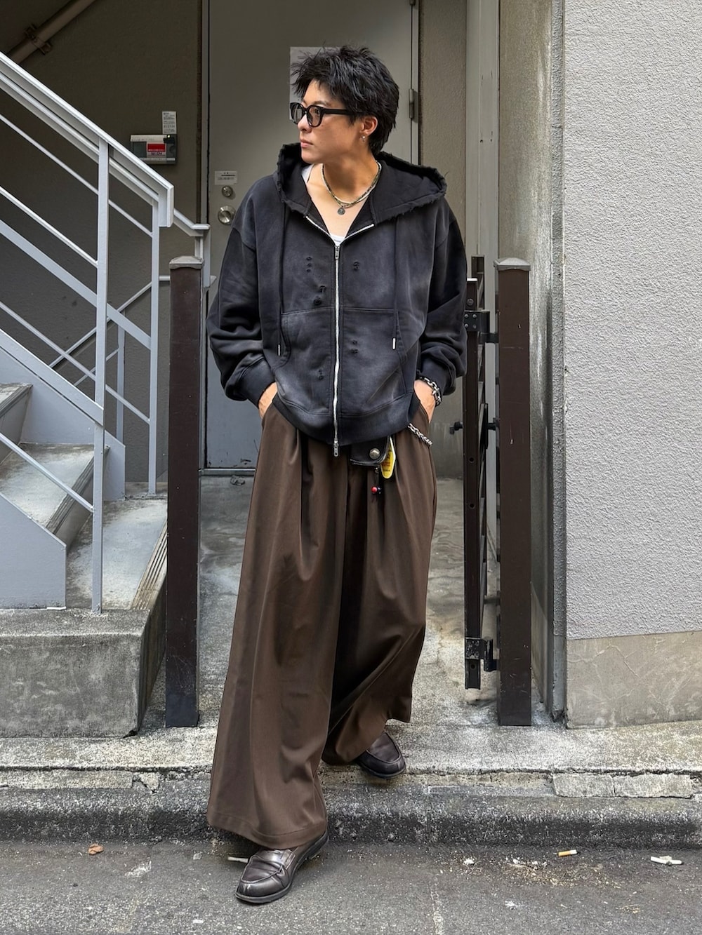 ブラック系のパーカー、ブラウン系のスラックス、グレー系のローファーを着用したメンズの秋コーディネートの2枚目の写真