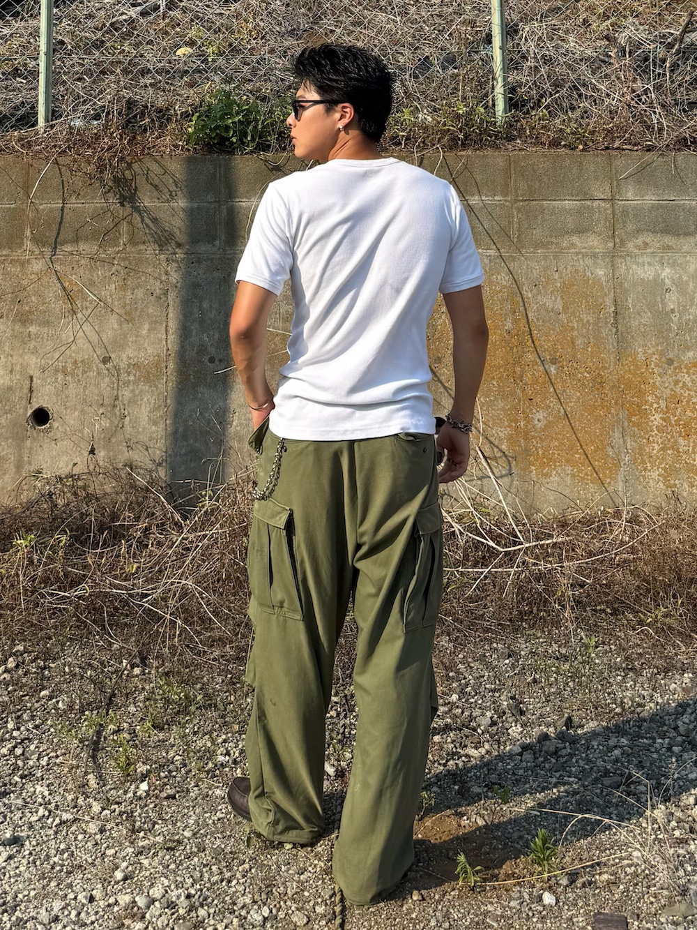 ホワイト系のTシャツ/カットソー、グレー系のローファー、グリーン系のパンツを着用したメンズの夏コーディネートの3枚目の写真