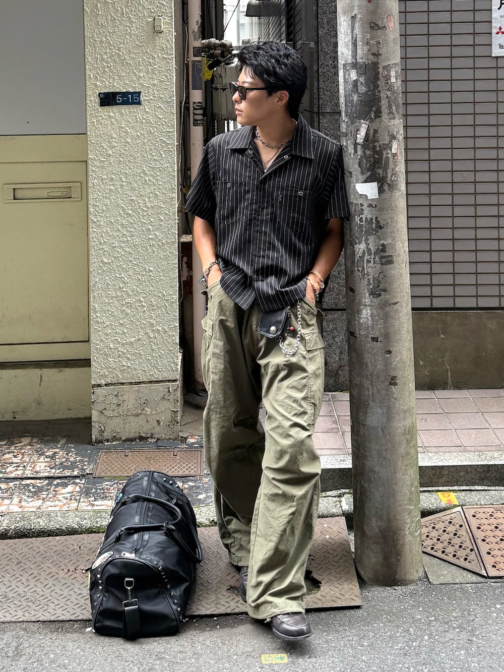 ブラック系のシャツ/ブラウス、ブラック系のボストンバッグ、グリーン系のカーゴパンツを着用したメンズの夏コーディネートの2枚目の写真