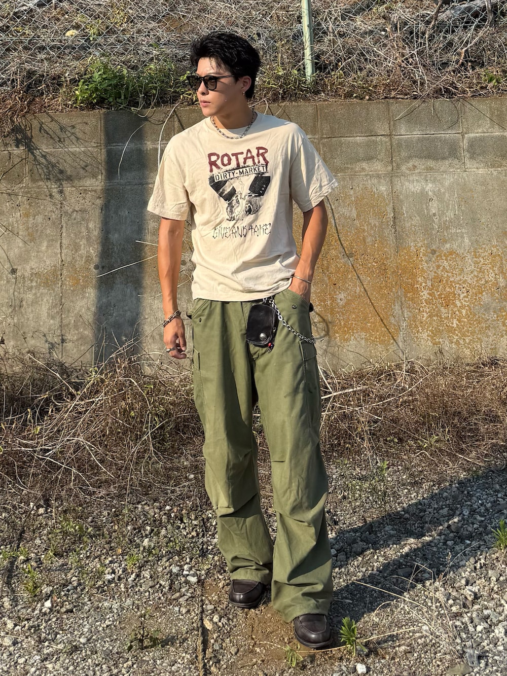 ベージュ系のTシャツ/カットソー、グレー系のローファー、グリーン系のパンツを着用したメンズの夏コーディネートの2枚目の写真