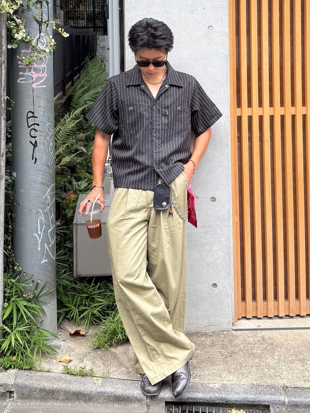 ブラック系のシャツ/ブラウス、ベージュ系のチノパンツ、グレー系のローファーを着用したメンズの夏コーディネートの2枚目の写真