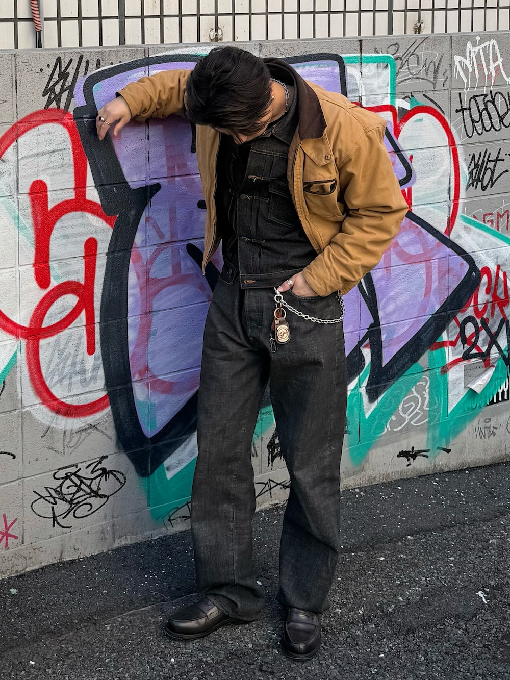 ブラウン系のブルゾン、ブラック系のデニムジャケット、ブラック系のデニムパンツを着用したメンズの春コーディネートの2枚目の写真