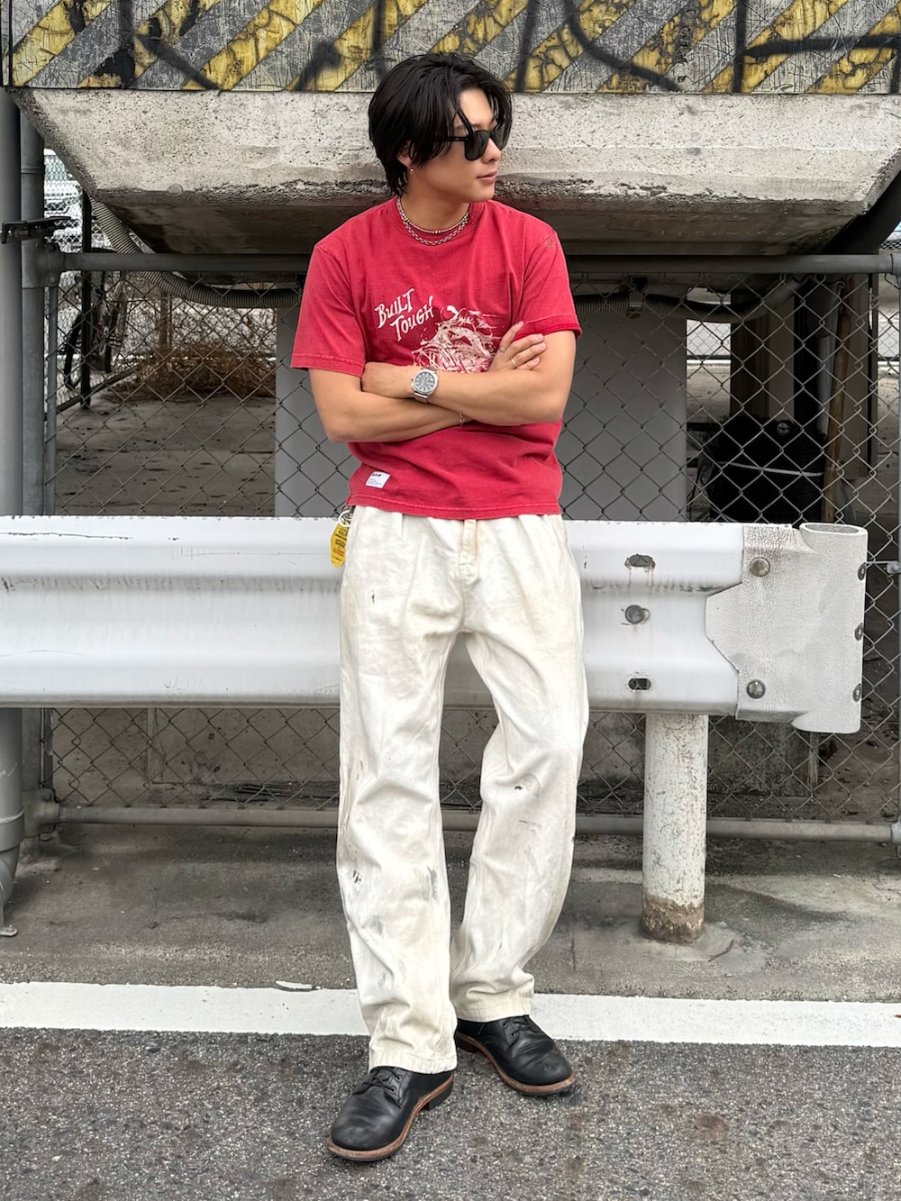 レッド系のTシャツ/カットソー、ブラック系のブーツ、ホワイト系のパンツを着用したメンズの春コーディネートの3枚目の写真