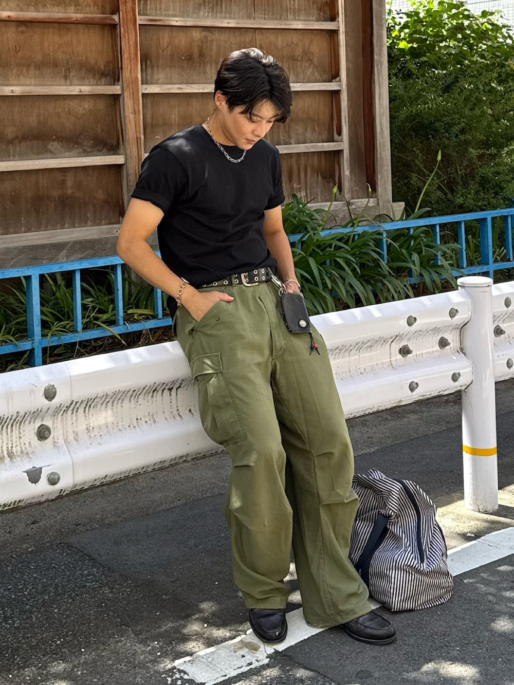 ブラック系のTシャツ/カットソー、グレー系のローファー、グリーン系のパンツを着用したメンズの夏コーディネートの2枚目の写真