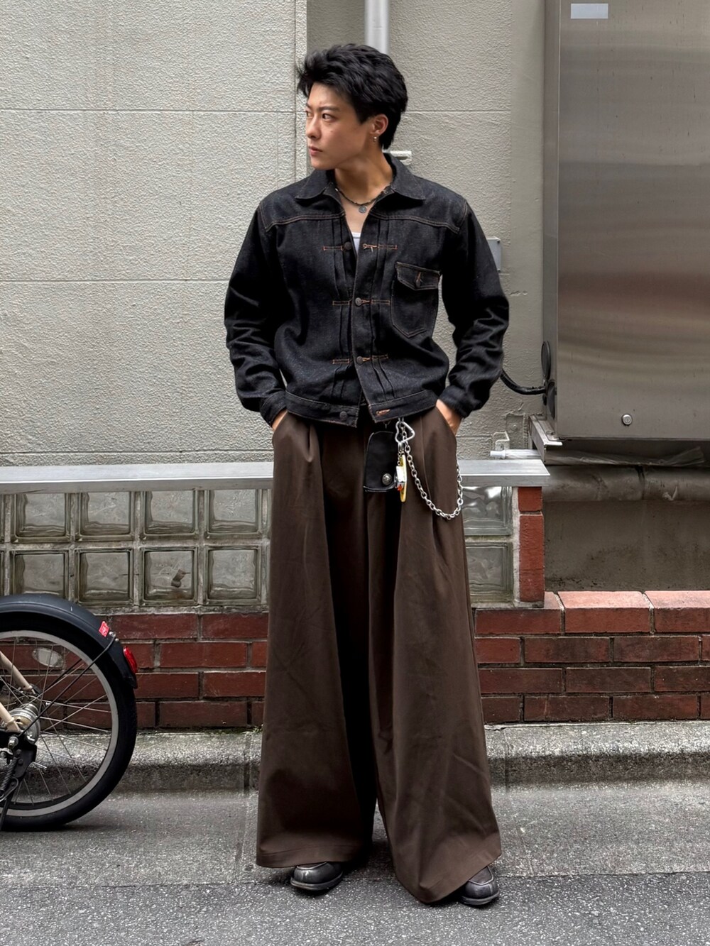ブラック系のデニムジャケット、ブラウン系のスラックス、グレー系のローファーを着用したメンズの秋コーディネートの2枚目の写真