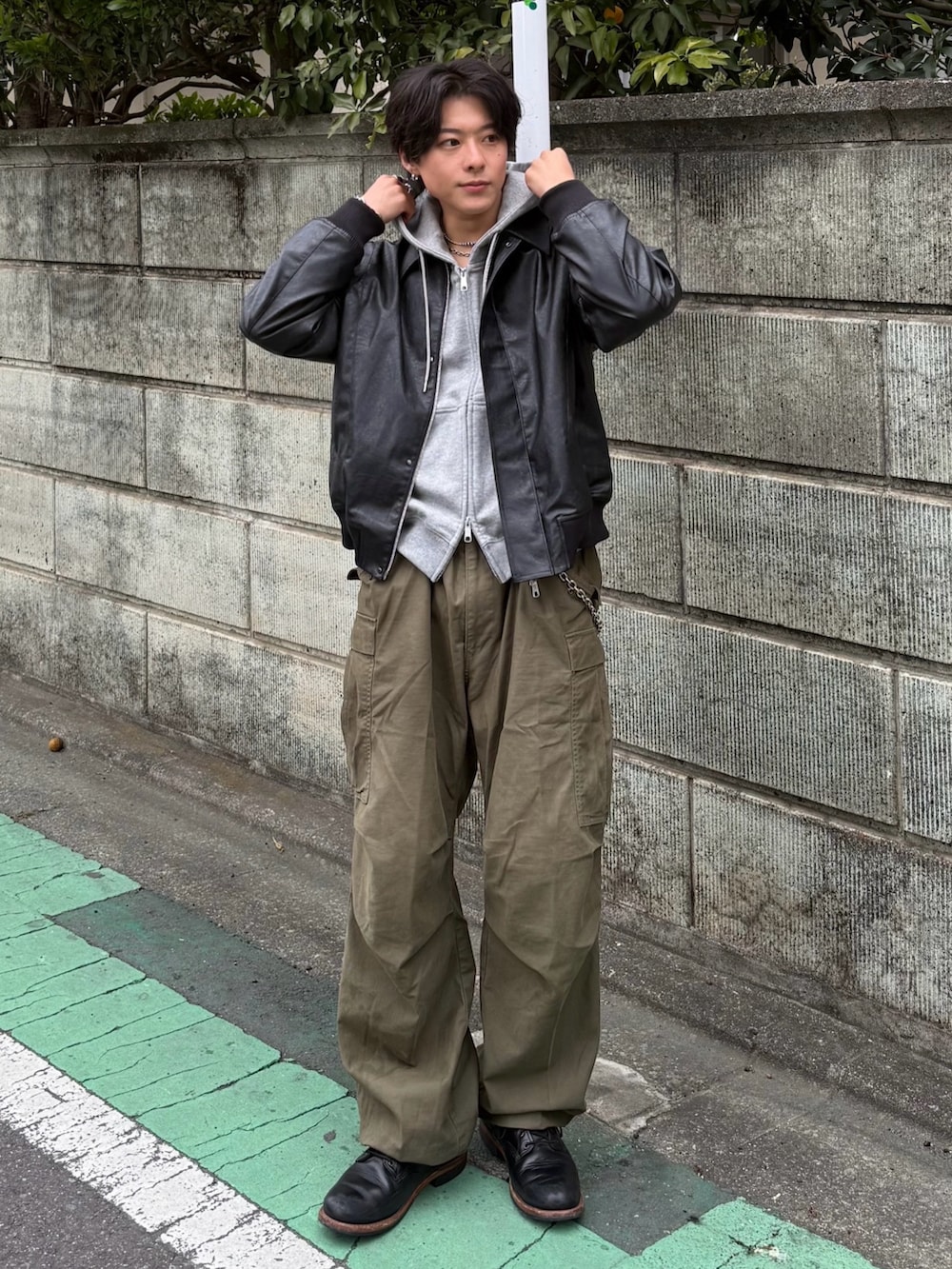 ブラック系のブルゾン、グレー系のパーカー、グリーン系のカーゴパンツを着用したメンズの冬コーディネートの2枚目の写真