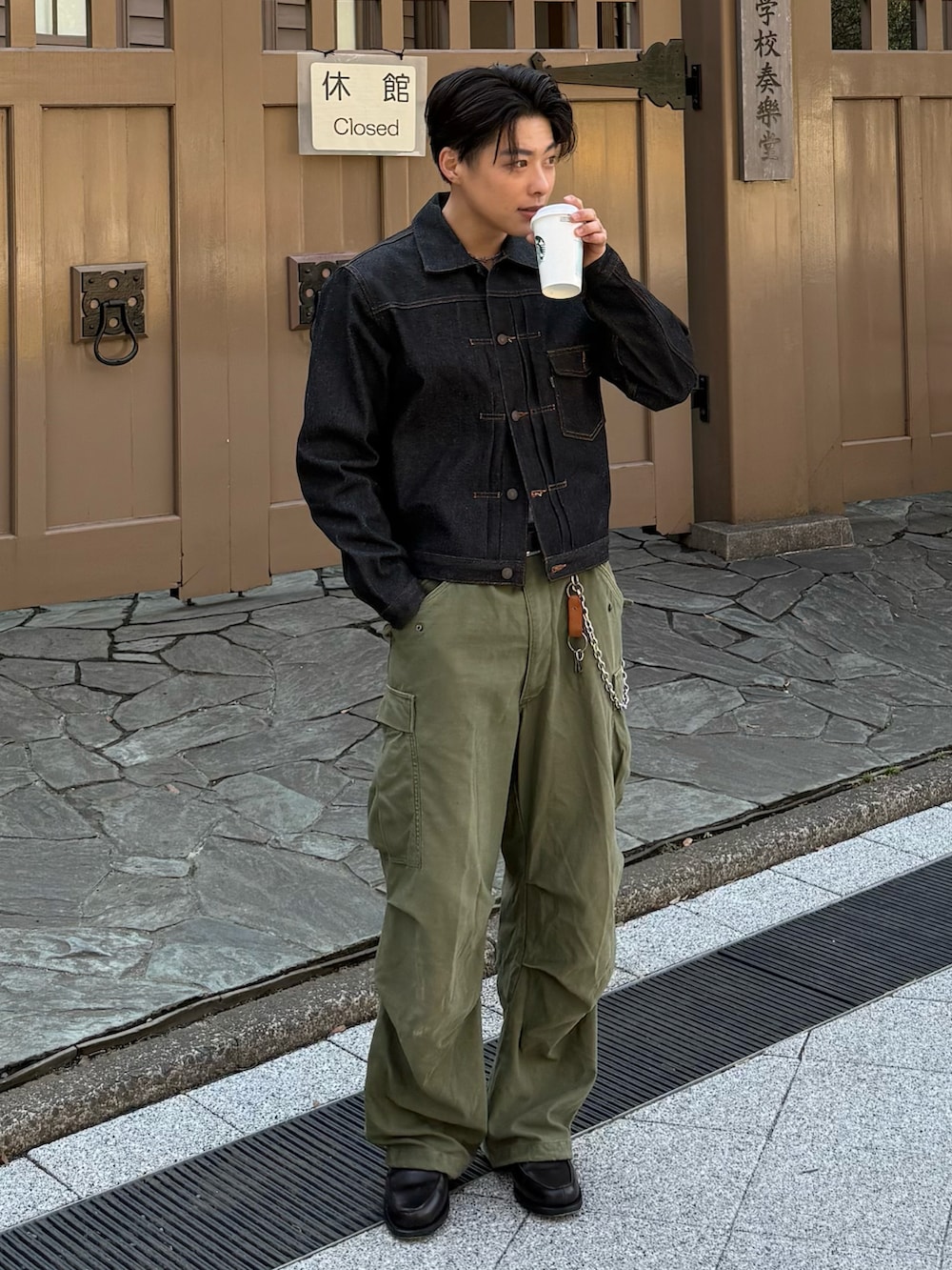 ブラック系のデニムジャケット、グレー系のローファー、グリーン系のパンツを着用したメンズの春コーディネートの2枚目の写真