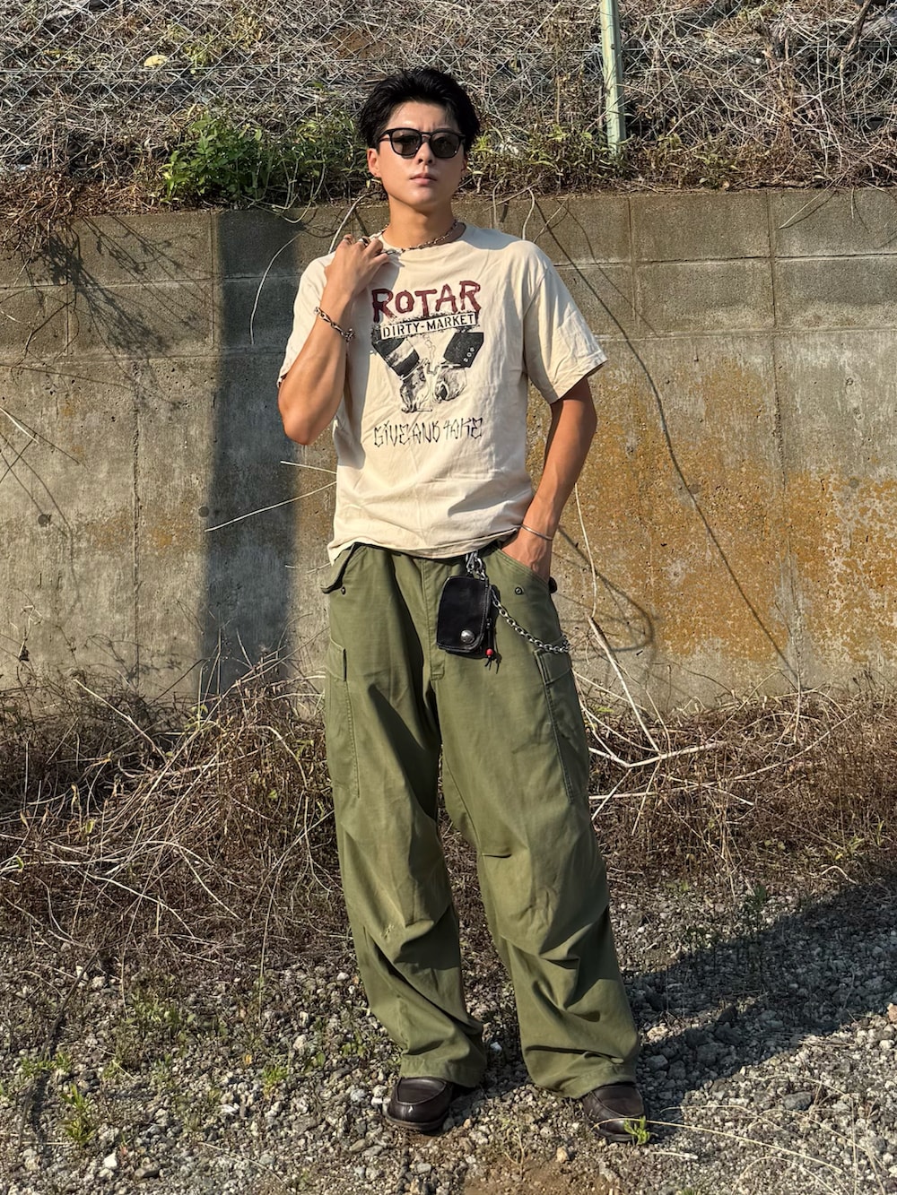 ベージュ系のTシャツ/カットソー、グレー系のローファー、グリーン系のパンツを着用したメンズの夏コーディネートの3枚目の写真