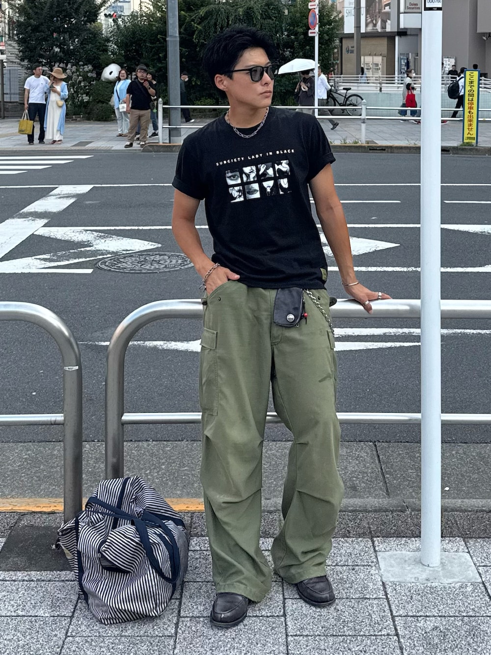 ブラック系のTシャツ/カットソー、グレー系のローファー、グリーン系のサングラスを着用したメンズの夏コーディネートの2枚目の写真