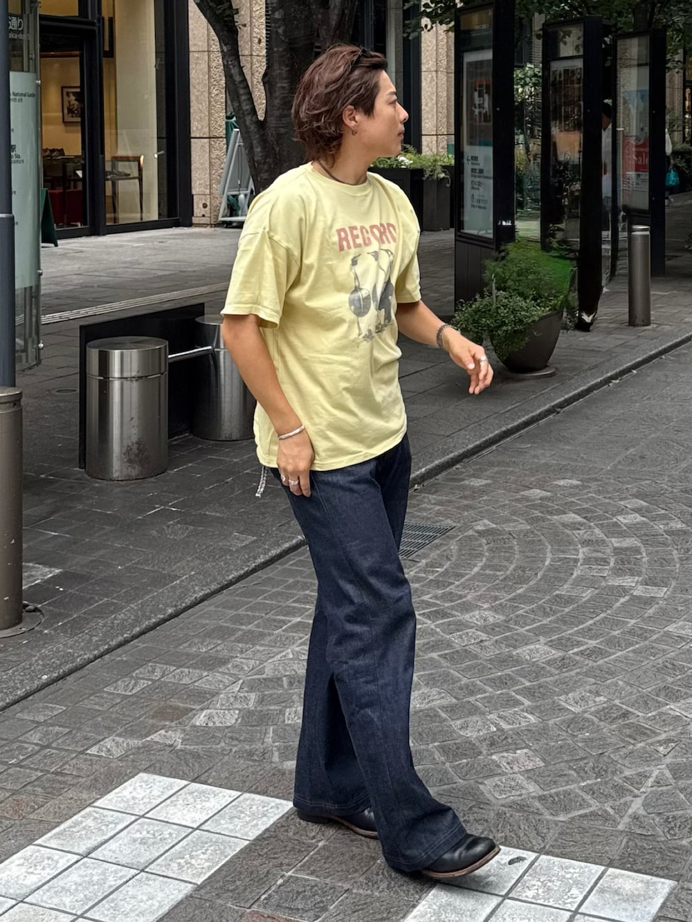 イエロー系のTシャツ/カットソー、ブラック系のデニムパンツ、ブラック系のブーツを着用したメンズの夏コーディネートの2枚目の写真