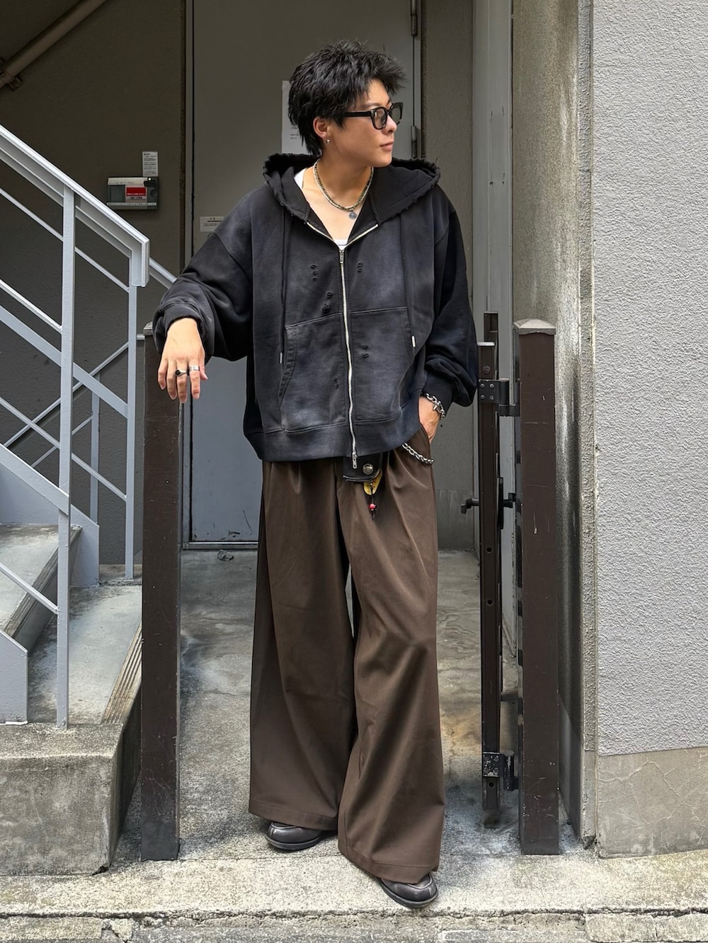 ブラック系のパーカー、ブラウン系のスラックス、グレー系のローファーを着用したメンズの秋コーディネートの3枚目の写真