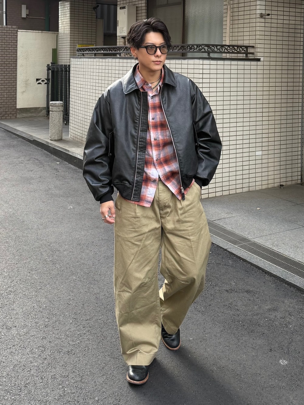 オレンジ系のシャツ/ブラウス、ブラック系のブルゾン、ベージュ系のチノパンツを着用したメンズの冬コーディネートの2枚目の写真