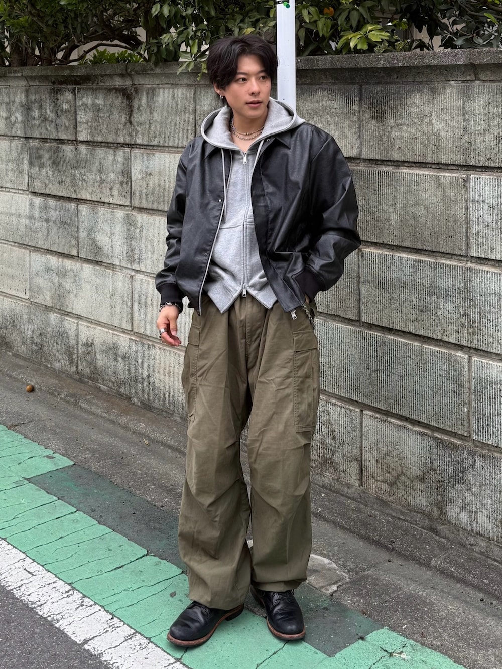 ブラック系のブルゾン、グレー系のパーカー、グリーン系のカーゴパンツを着用したメンズの冬コーディネートの3枚目の写真