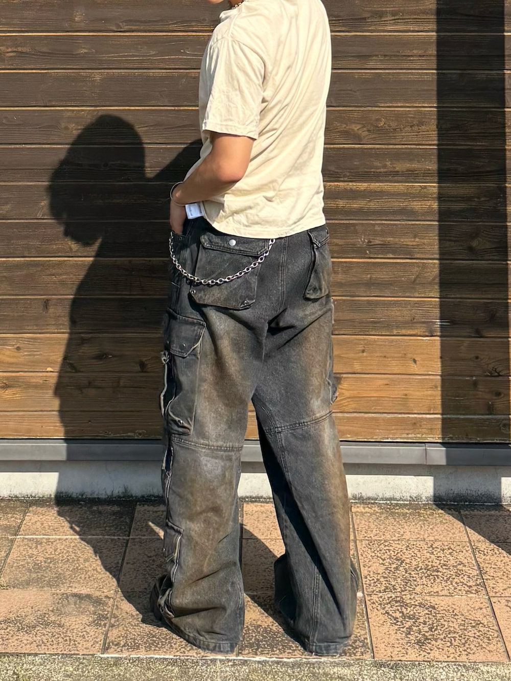 ベージュ系のTシャツ/カットソー、ブラック系のデニムパンツ、ブラック系のブーツを着用したメンズの夏コーディネートの3枚目の写真