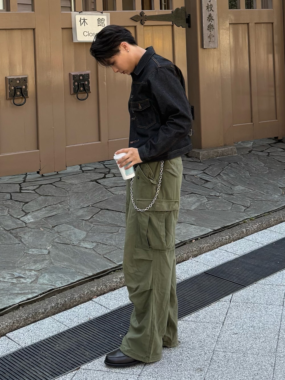 ブラック系のデニムジャケット、グレー系のローファー、グリーン系のパンツを着用したメンズの春コーディネートの3枚目の写真