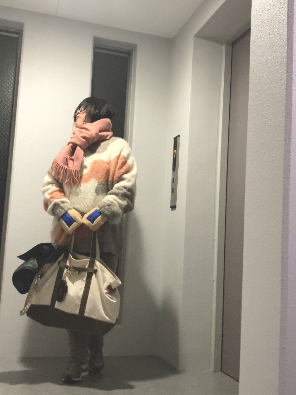 ベージュ系のニット/セーター、グリーン系のトートバッグ、ホワイト系のスニーカーを着用したレディースの冬コーディネートの2枚目の写真