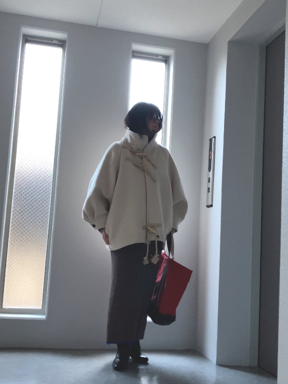 グレー系のニット/セーター、ブラウン系のスカート、ブラウン系のブーツを着用したレディースの冬コーディネートの2枚目の写真