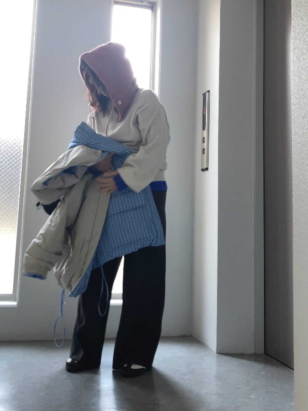 ブルー系のダウンジャケット/コート、ホワイト系のニット/セーター、ブラック系のバッグを着用したレディースの冬コーディネートの4枚目の写真