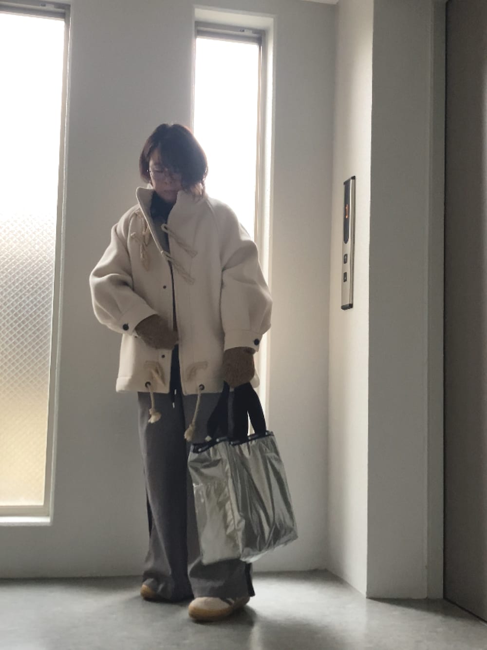 ベージュ系のベスト、グレー系のカーディガン/ボレロ、ホワイト系のダッフルコートを着用したレディースの冬コーディネートの4枚目の写真