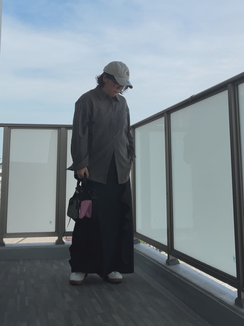 ブラック系のショルダーバッグ、シルバー系のスニーカー、ブラック系のスカートを着用したレディースの秋コーディネートの2枚目の写真