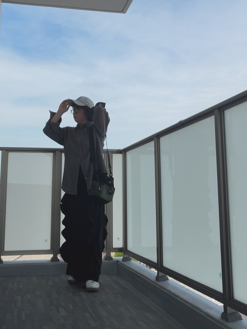 ブラック系のショルダーバッグ、シルバー系のスニーカー、ブラック系のスカートを着用したレディースの秋コーディネートの4枚目の写真