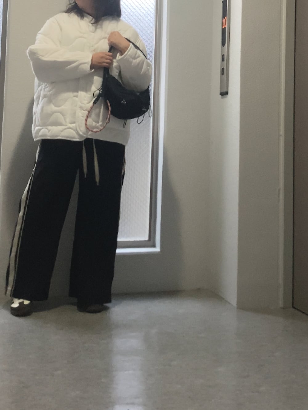 ホワイト系のスニーカー、ブラック系のバッグ、ブラック系のその他パンツを着用したレディースの秋コーディネートの3枚目の写真